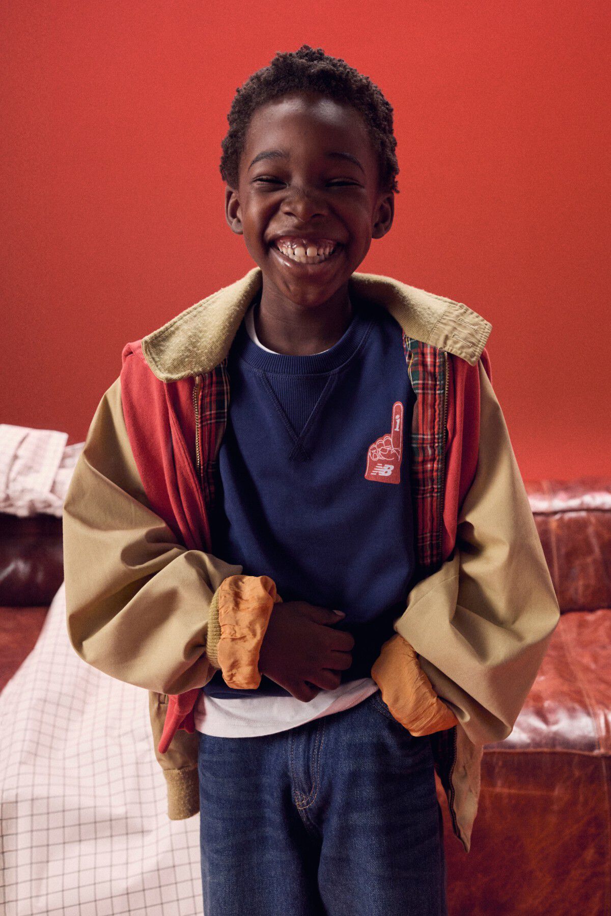 Young kid smiling in front of a red couch.