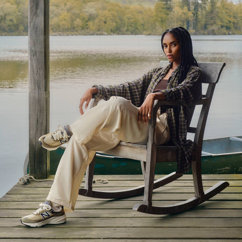 A woman sitting on a porch with a lake behind her. 