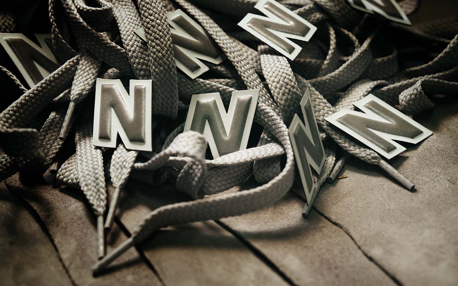 A pile of New Balance logos and shoestrings laying on a piece of suede. 