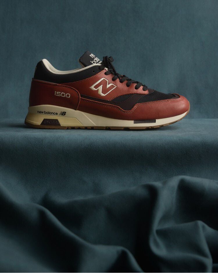 A New Balance Made in UK sneaker sitting in a flowing blue fabric studio backdrop. 