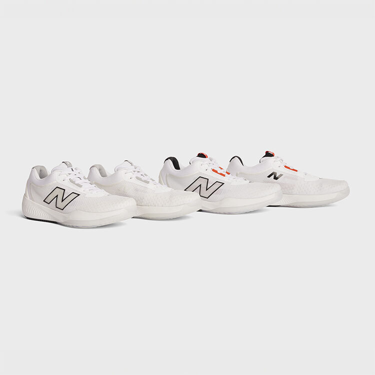 Men's and women's all white tennis shoes sitting on a grey background.