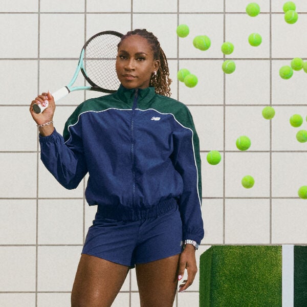 Coco Gauff standing with a racket while tennis balls fall around her.  