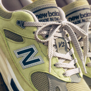 A pair of New Balance Made in UK sneakers in front of a rabbit in a brown textured studio environment. 